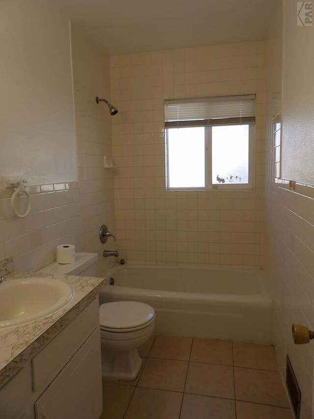 full bathroom featuring shower / tub combination, toilet, tile patterned flooring, vanity, and tile walls