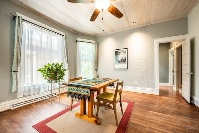 dining area featuring a ceiling fan, wood finished floors, a baseboard heating unit, wooden ceiling, and ornamental molding