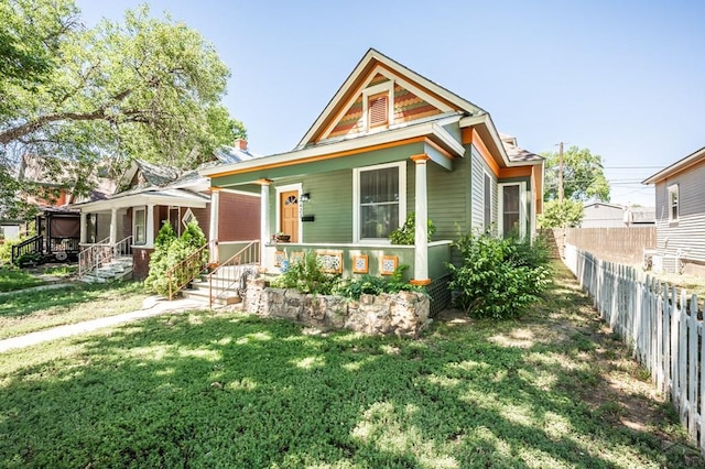view of front of home featuring a fenced backyard, a front lawn, and covered porch