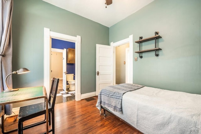 bedroom with baseboards, ensuite bath, wood finished floors, and a ceiling fan