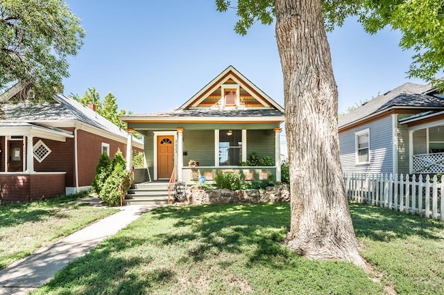 view of front of property with fence, a front lawn, and covered porch