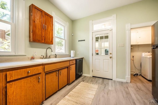 kitchen featuring brown cabinets, light wood finished floors, light countertops, dishwasher, and a sink