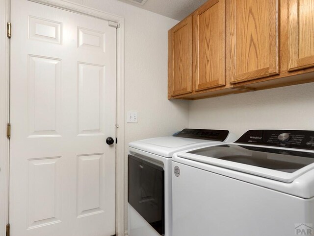 clothes washing area featuring cabinet space and independent washer and dryer