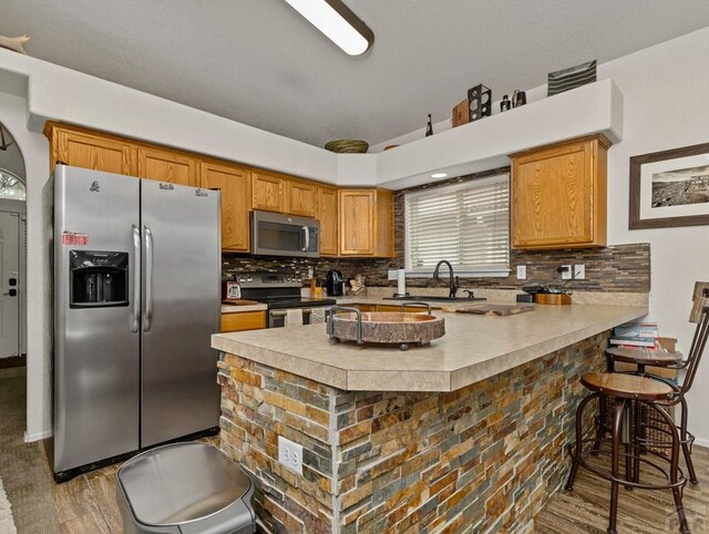 kitchen with stainless steel appliances, brown cabinetry, light countertops, and decorative backsplash