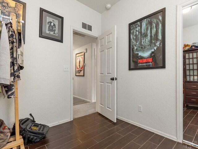 corridor featuring wood finish floors, visible vents, and baseboards