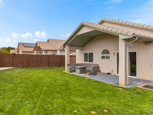 back of property featuring an outdoor living space with a fire pit, stucco siding, a lawn, a patio area, and a fenced backyard