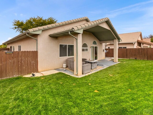 back of house featuring a patio, a tile roof, fence, a yard, and stucco siding