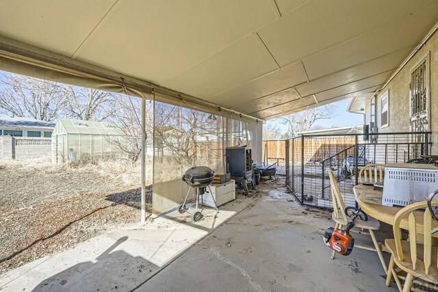 view of patio with an outbuilding, a grill, a greenhouse, and fence