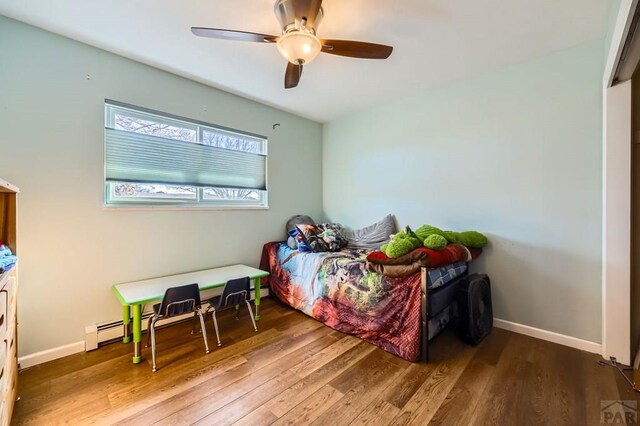 bedroom featuring a ceiling fan, baseboards, and wood finished floors