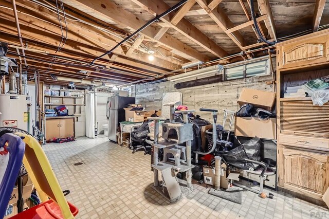 unfinished basement with light floors, water heater, and freestanding refrigerator