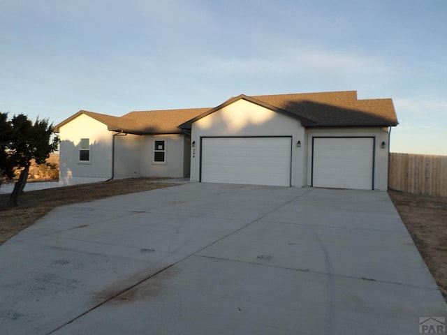 ranch-style house with a garage, driveway, fence, and stucco siding