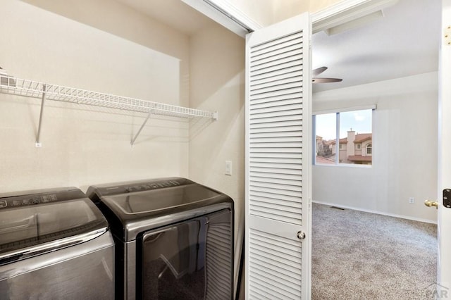 clothes washing area featuring washing machine and dryer, light carpet, laundry area, a ceiling fan, and baseboards