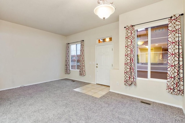 entrance foyer featuring light colored carpet, visible vents, and baseboards