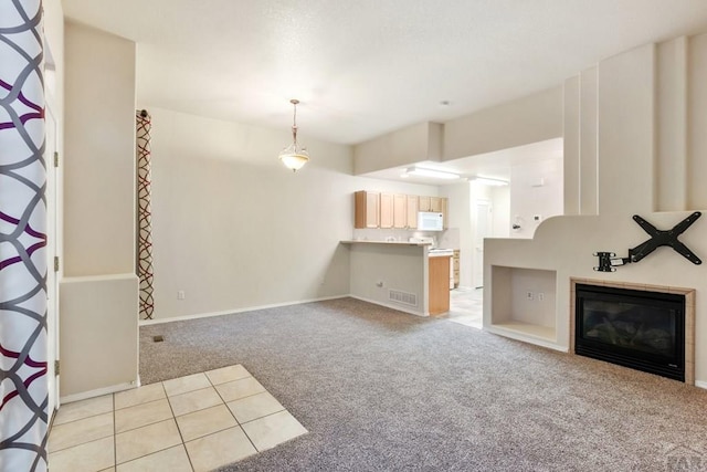 unfurnished living room with a glass covered fireplace, light carpet, visible vents, and baseboards