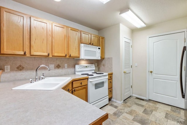 kitchen with light countertops, white appliances, a sink, and decorative backsplash