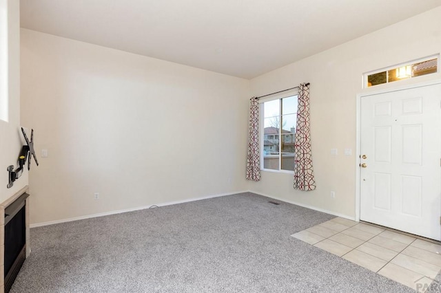 foyer featuring light carpet and baseboards