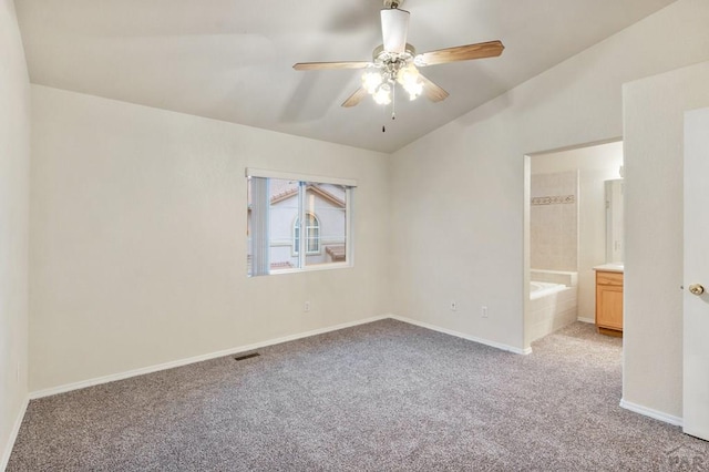 spare room with light colored carpet, visible vents, a ceiling fan, vaulted ceiling, and baseboards