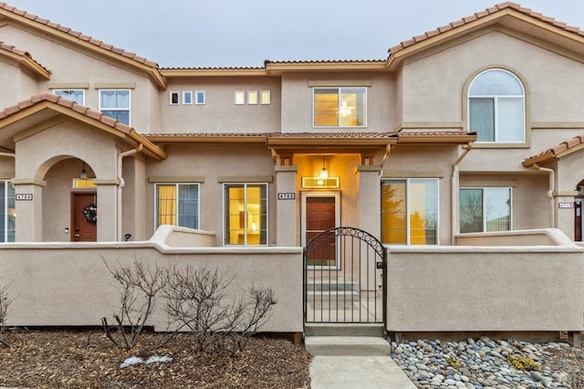 view of front facade featuring a fenced front yard, a gate, and stucco siding