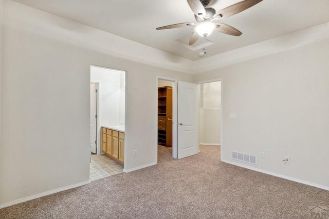 unfurnished bedroom featuring light carpet, baseboards, a spacious closet, and visible vents