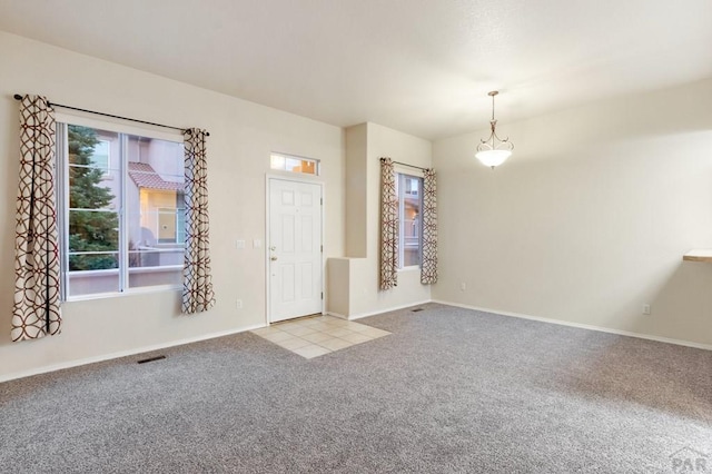 foyer entrance featuring baseboards, visible vents, and light colored carpet