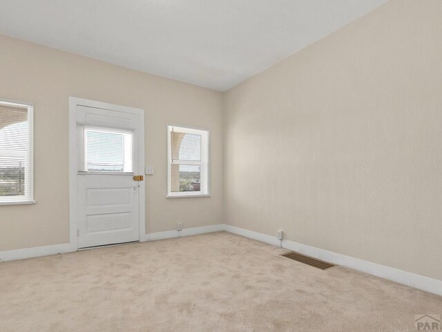 spare room with light carpet, a healthy amount of sunlight, and visible vents