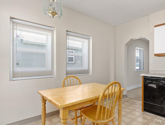 dining room with arched walkways, light floors, plenty of natural light, and baseboards