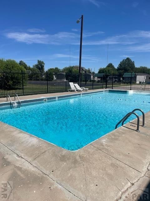 pool with a patio area and fence