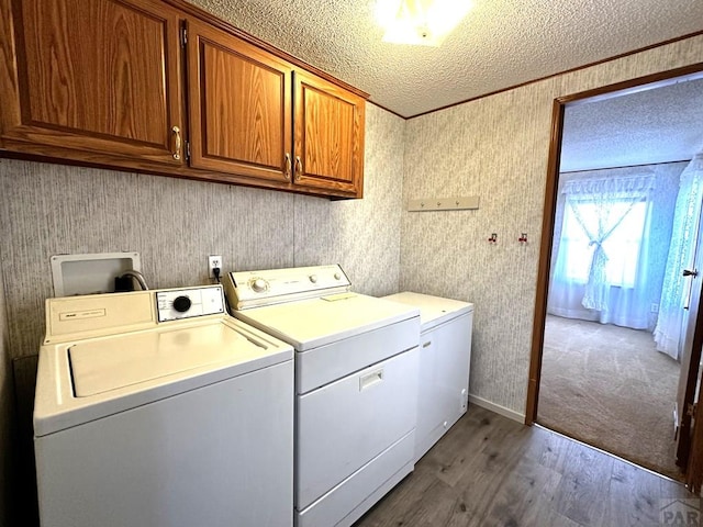 laundry room with a textured ceiling, cabinet space, washer and clothes dryer, dark wood finished floors, and wallpapered walls