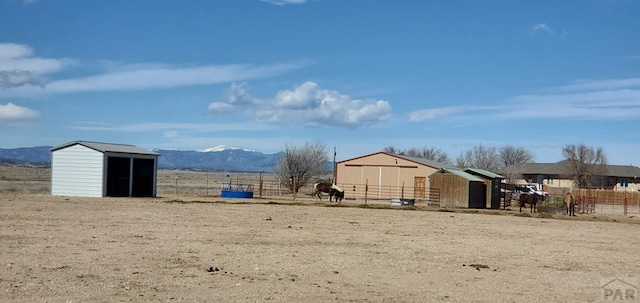 view of yard with an outbuilding, a pole building, fence, and a mountain view