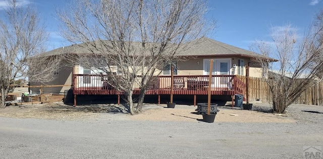 back of house with roof with shingles and a wooden deck