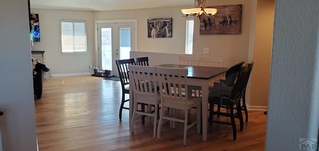 dining room with an inviting chandelier, french doors, baseboards, and hardwood / wood-style flooring