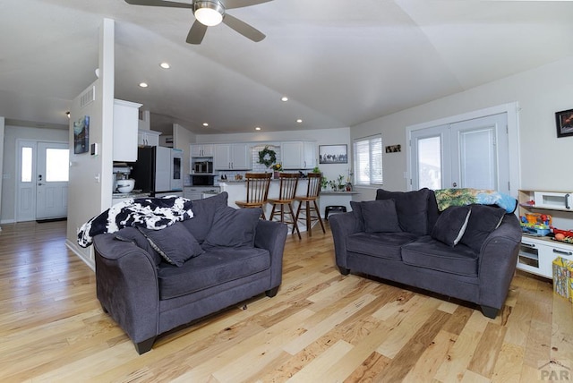 living room featuring light wood-type flooring, visible vents, vaulted ceiling, and recessed lighting