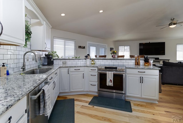 kitchen with appliances with stainless steel finishes, open floor plan, a peninsula, a sink, and a wealth of natural light