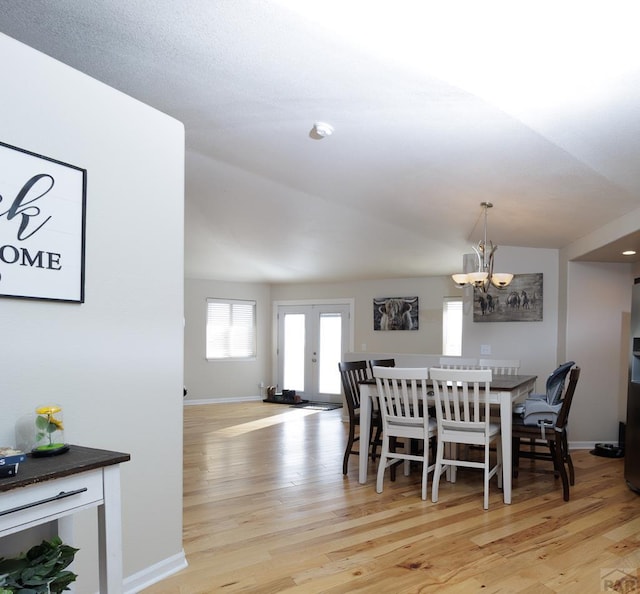 dining room with light wood-type flooring, an inviting chandelier, baseboards, and french doors