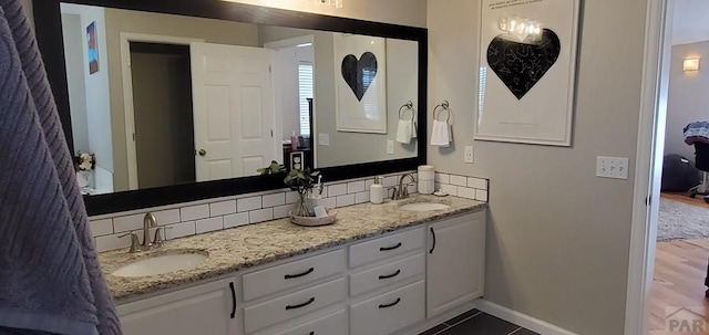 bathroom featuring double vanity, baseboards, a sink, and tile patterned floors