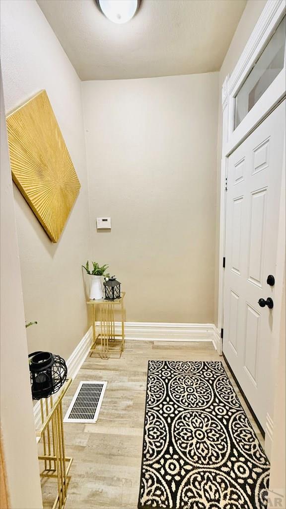 entryway with baseboards, wood finished floors, and visible vents