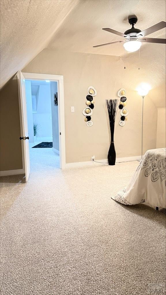 carpeted bedroom with baseboards, ceiling fan, vaulted ceiling, and a textured ceiling