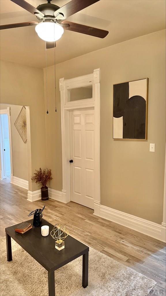 interior space featuring a ceiling fan, baseboards, and light wood-style floors