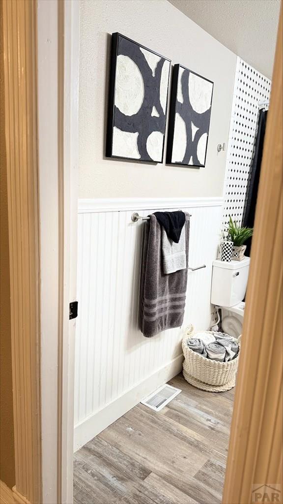 mudroom featuring visible vents, a textured ceiling, wainscoting, and wood finished floors