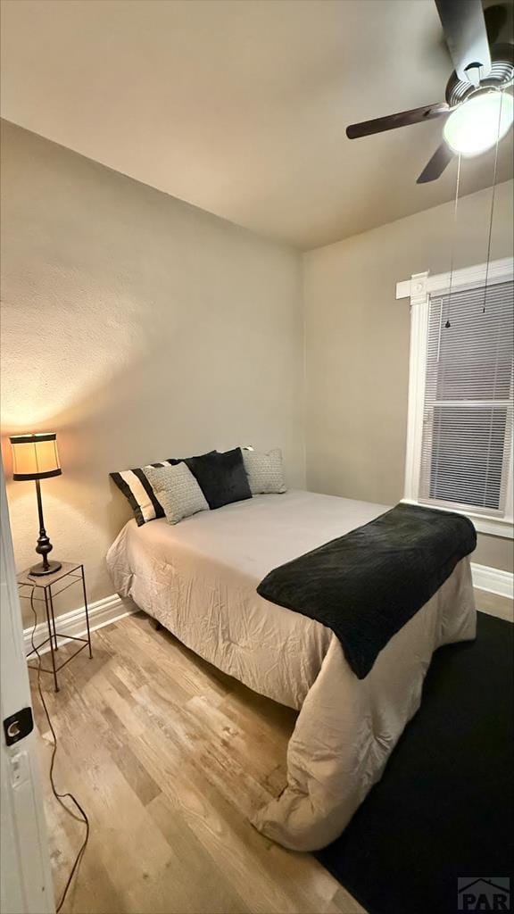 bedroom featuring baseboards, a ceiling fan, and wood finished floors