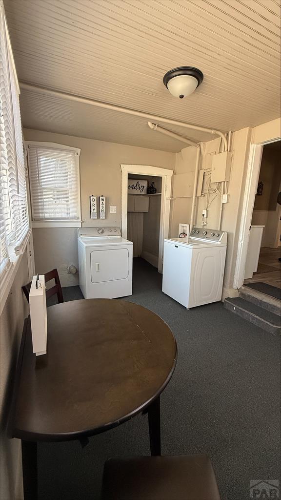 clothes washing area featuring laundry area, dark carpet, and washing machine and clothes dryer