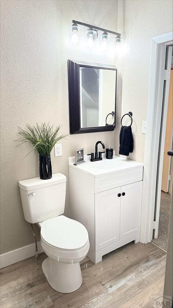 bathroom with a textured wall, wood finished floors, and toilet