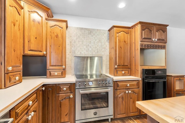 kitchen featuring brown cabinets, tasteful backsplash, recessed lighting, stainless steel stove, and wooden counters