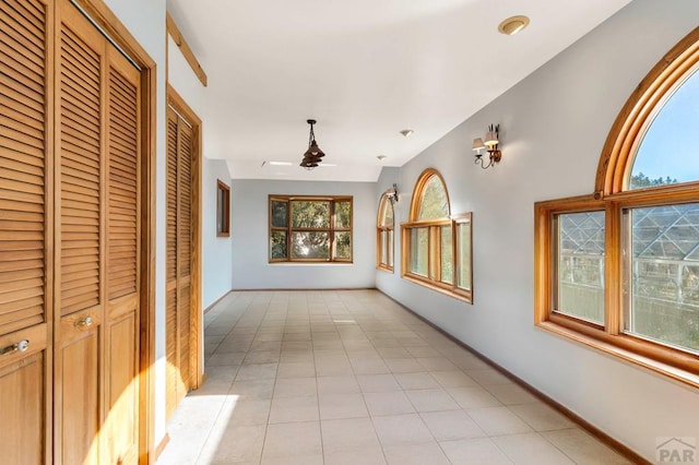 hallway with light tile patterned flooring and baseboards