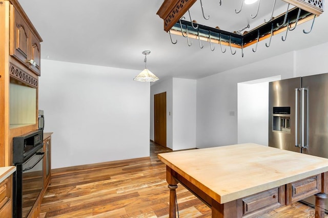 kitchen featuring pendant lighting, light countertops, high quality fridge, wood finished floors, and oven