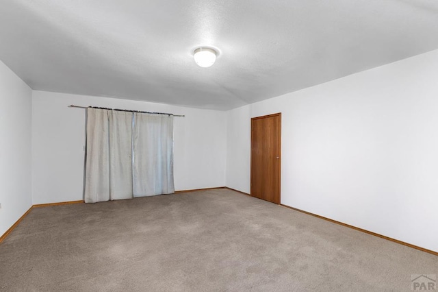 unfurnished room with light carpet and baseboards