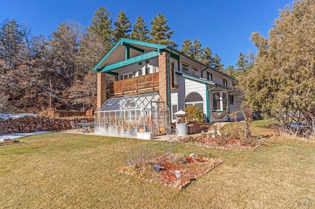 view of property exterior featuring a balcony, a patio, a lawn, and an exterior structure