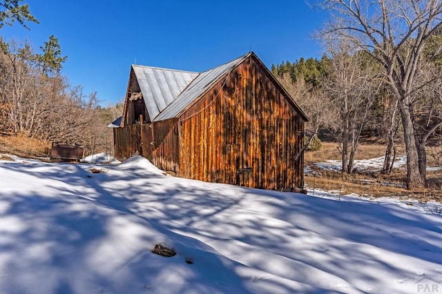 snow covered property with metal roof and a barn