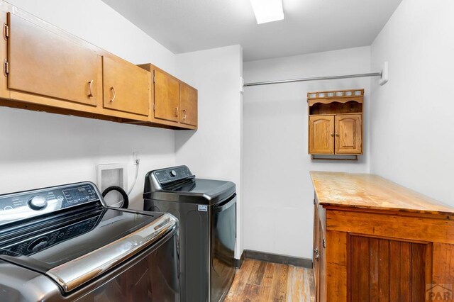 washroom with light wood finished floors, washer and clothes dryer, and cabinet space