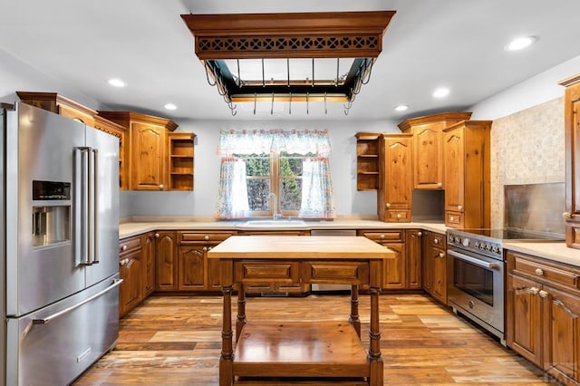 kitchen featuring premium appliances, light countertops, a sink, and open shelves